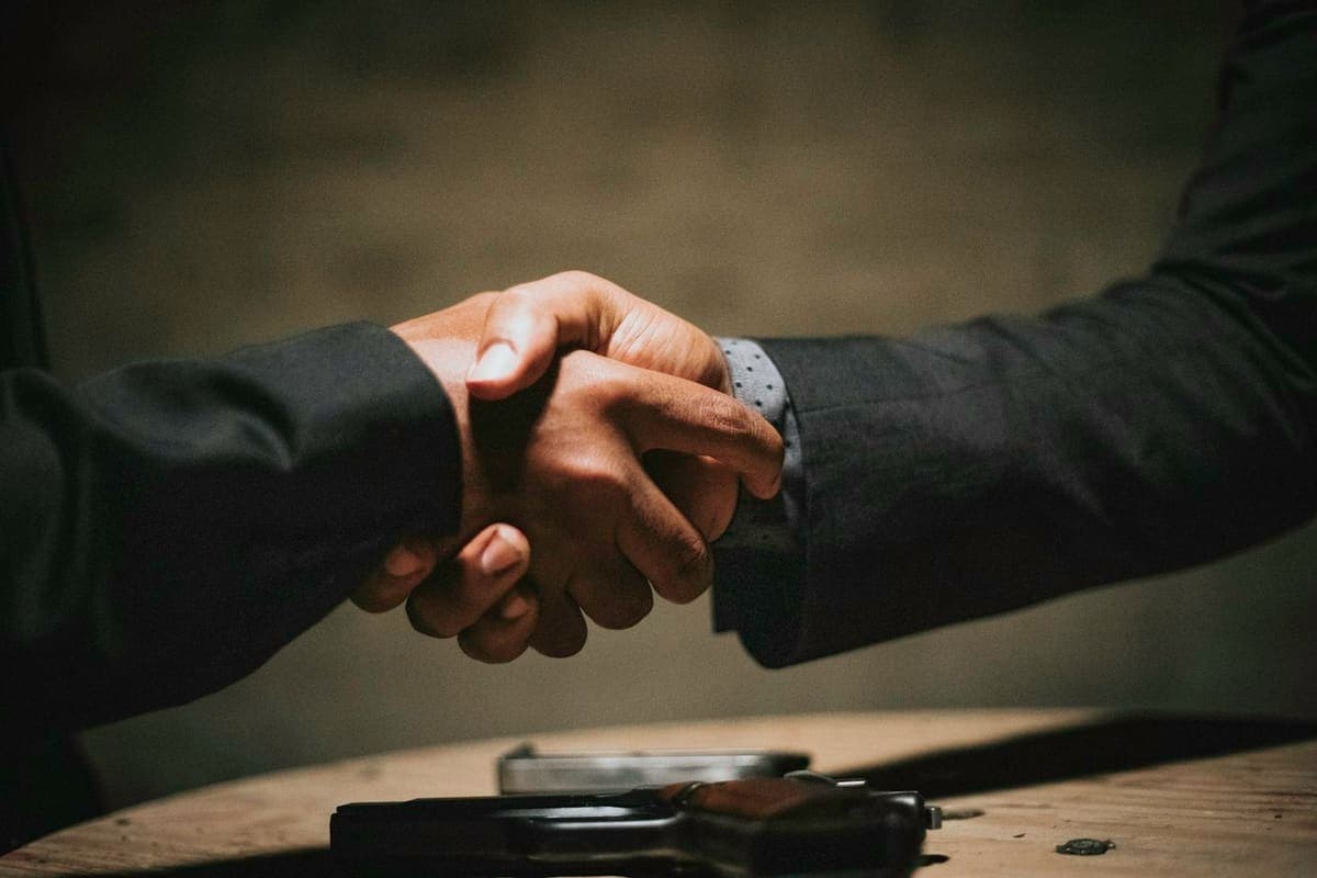 Two people shaking hands over a wooden table