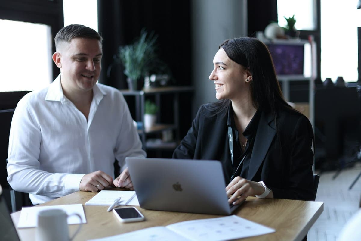 A man and a woman smiling while working on a laptop together
